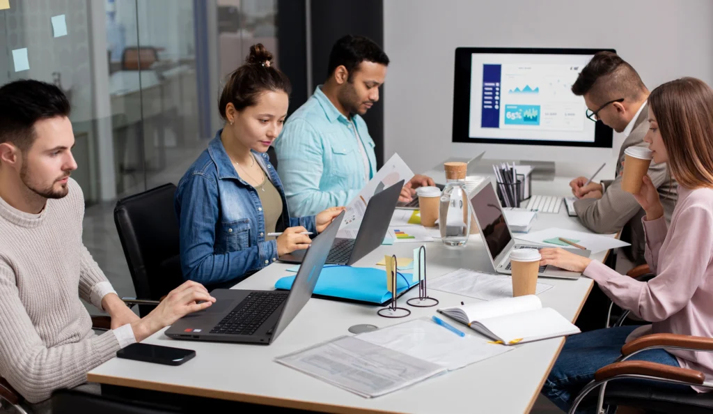 A team of people working together on laptops, showcasing collaboration in a bright office space.